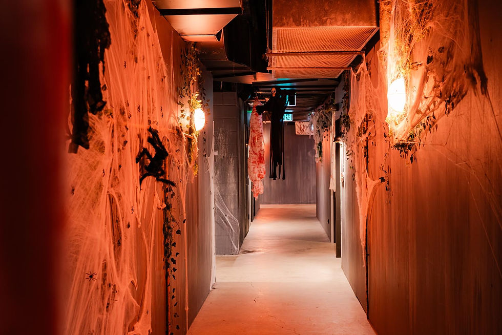 Spooky orange-lit hallway draped in fake cobwebs, with hanging ghost decorations and eerie Halloween decor לאורך corridor