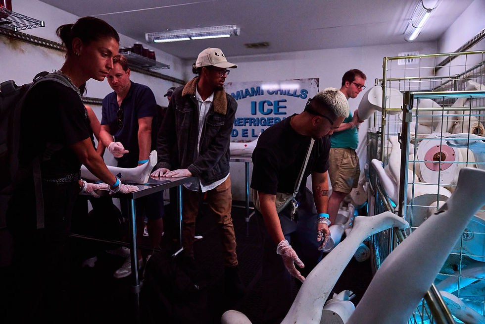 People examine mannequin legs in a dimly lit room with a sign reading "ICE." They wear gloves, and blue light adds an eerie mood.