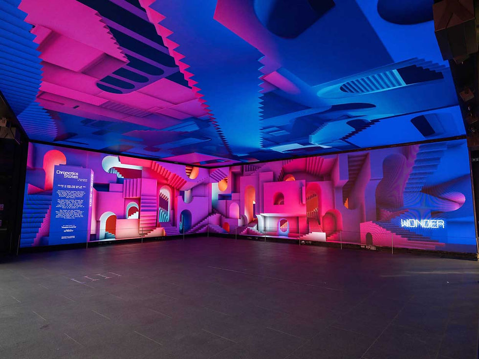 Colorful neon art installation with pink and blue 3D geometric walls and ceiling; signs read Chromatics States and WONDER.