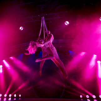 Two people suspended by ropes move in the air