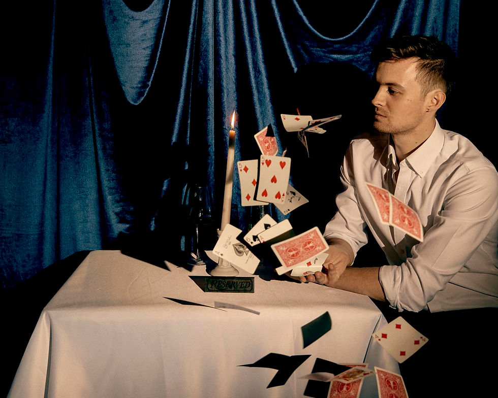 Man at a candlelit table with floating playing cards, blue drapes behind, and a RESERVED sign in a moody casino-like scene.