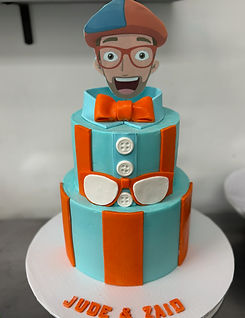 Round Two Tier Cake with Orange and Turquoise Stripes, White Fondant Decorations, and a Character Man on Top