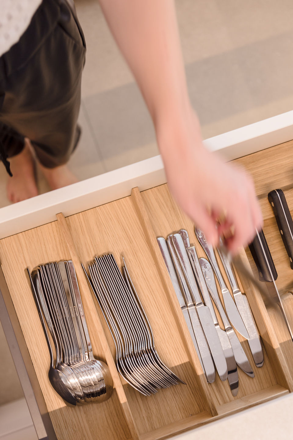Eine geöffnete Schublade mit Besteckeinsatz aus Holz: ordentlich sortierte Messer, Gabeln und Löffel