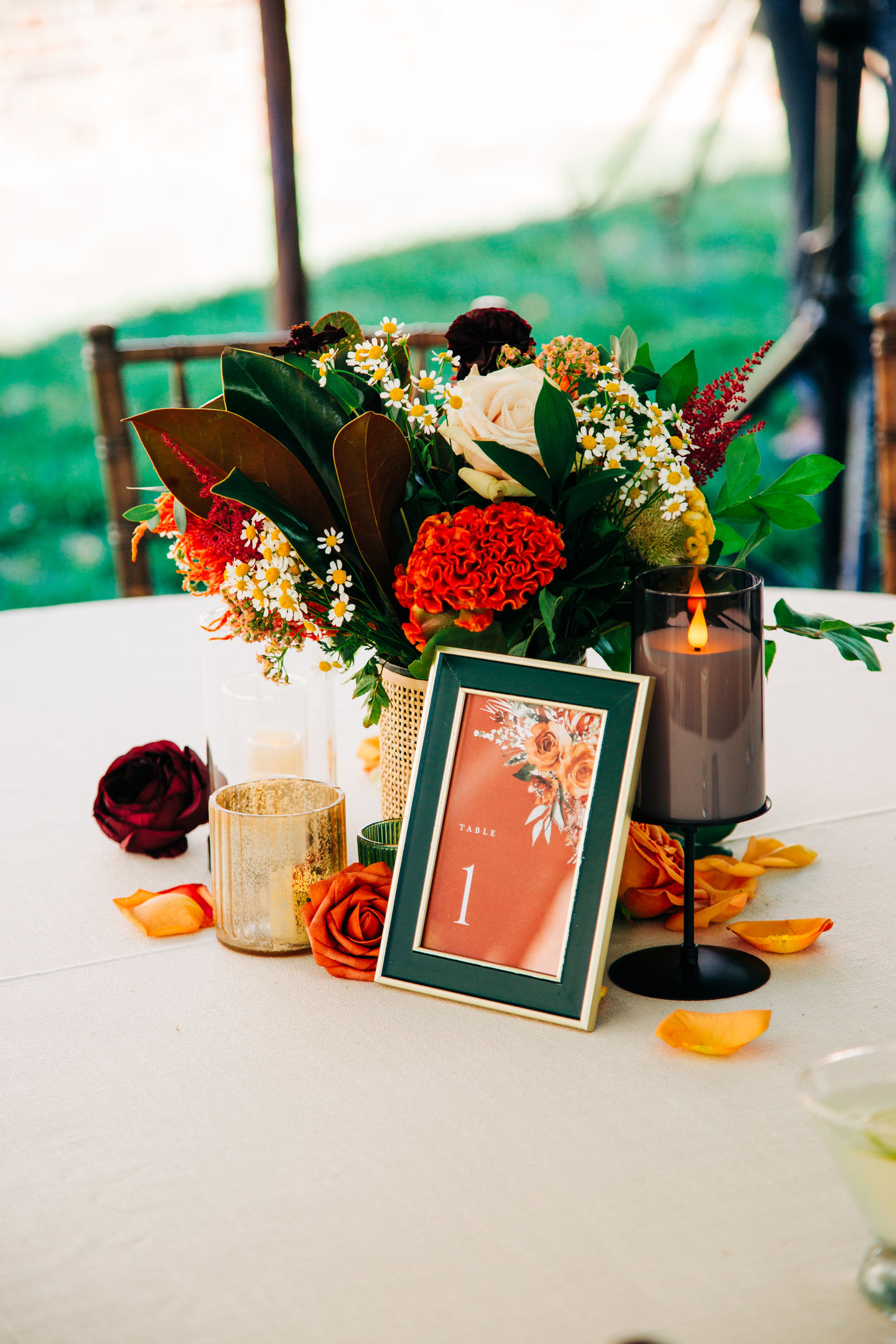 Floral wedding table arrangement with orange and red flowers and printed table signage by Tia’s Food of Love.