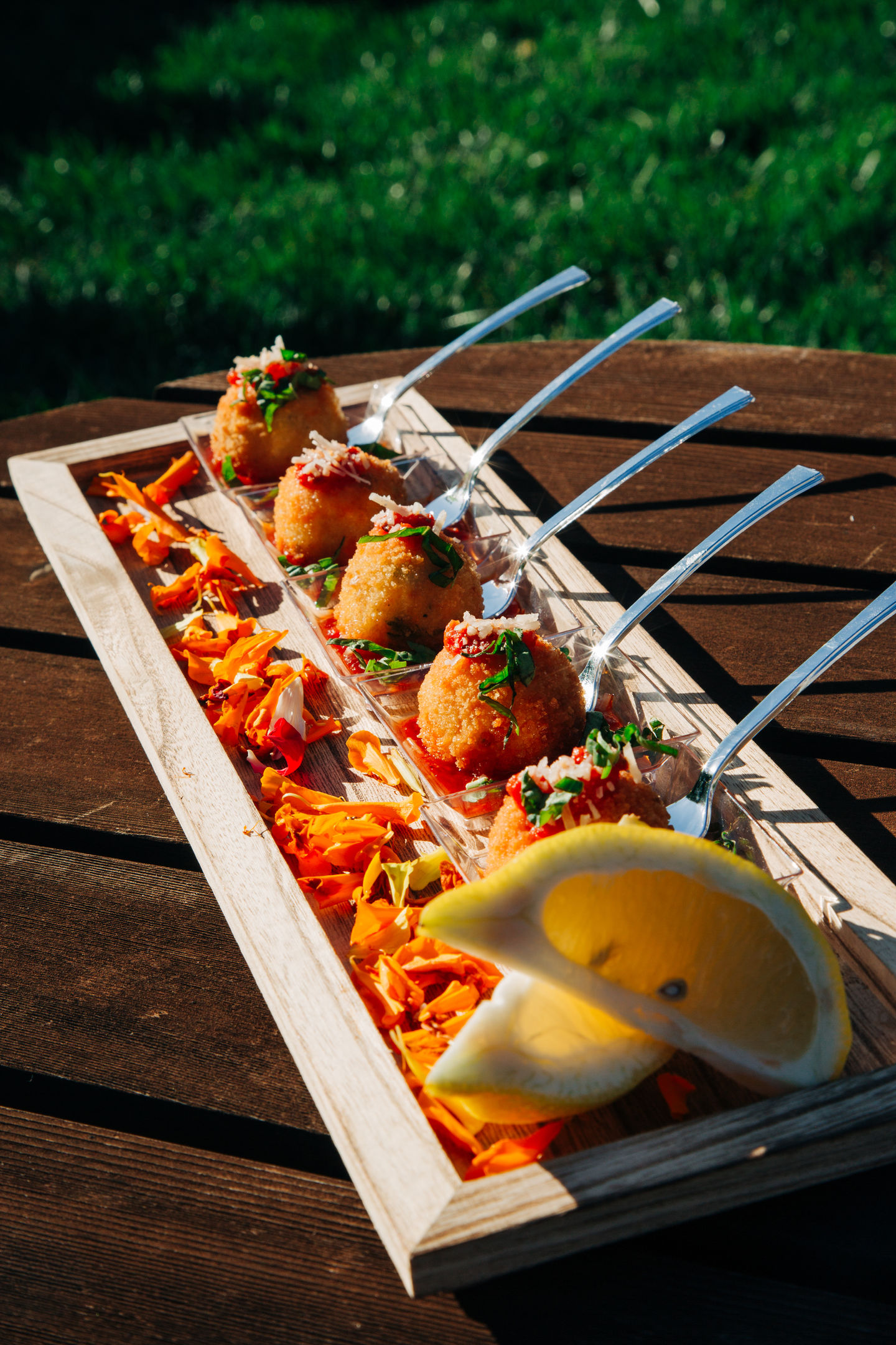Wooden tray with appetizer skewers and lemon garnish served at a Tia’s Food of Love wedding.