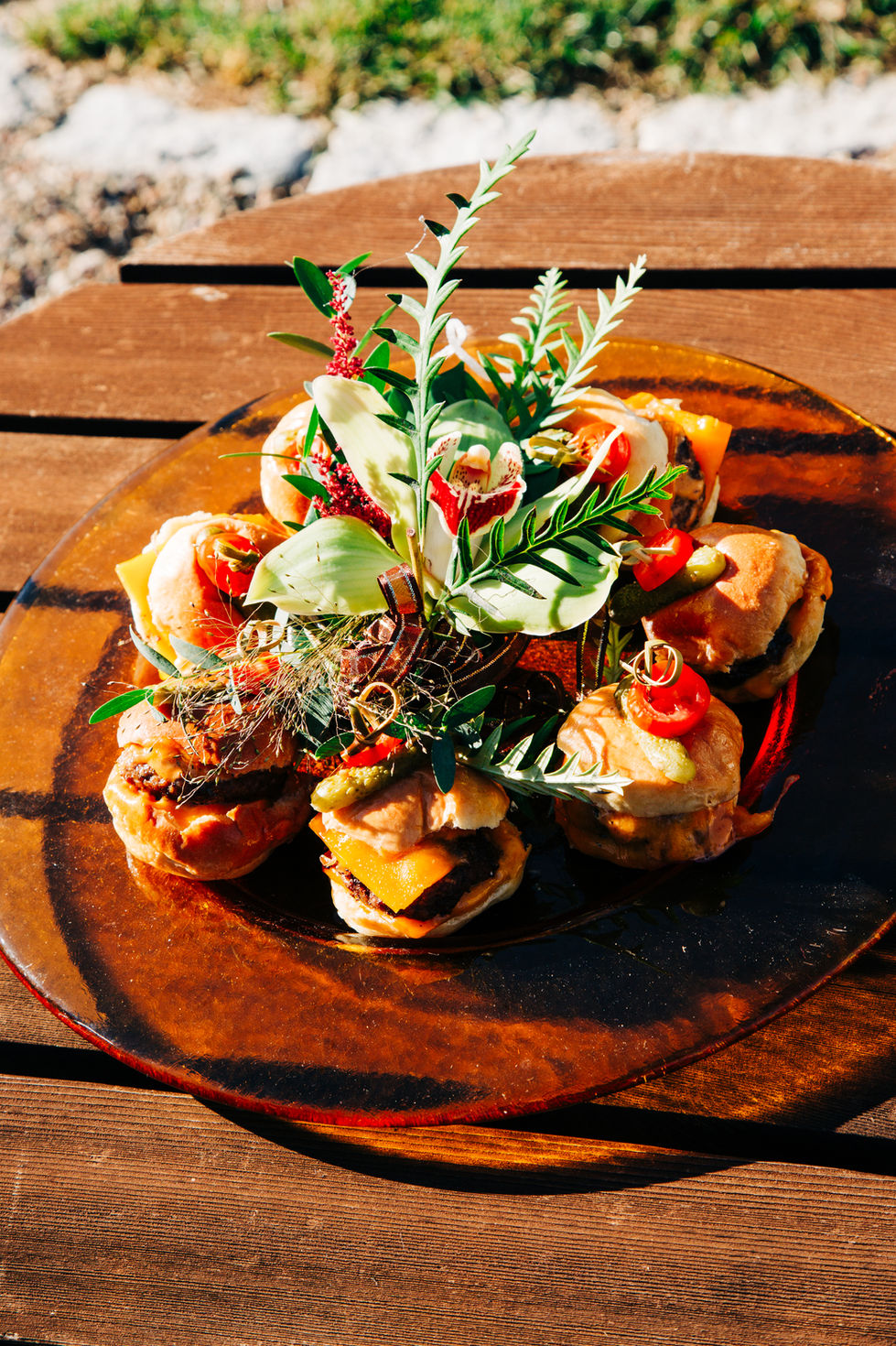 Plated wedding appetizers burger sliders garnished with herbs and flowers by Tia’s Food of Love.