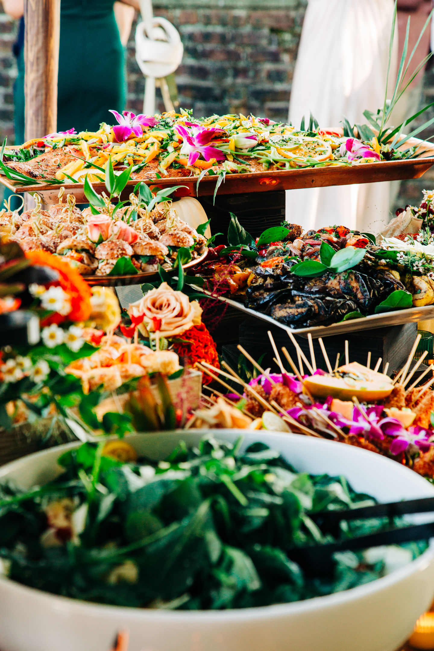Wedding catering display with assorted salads and floral garnishes by Tia’s Food of Love.