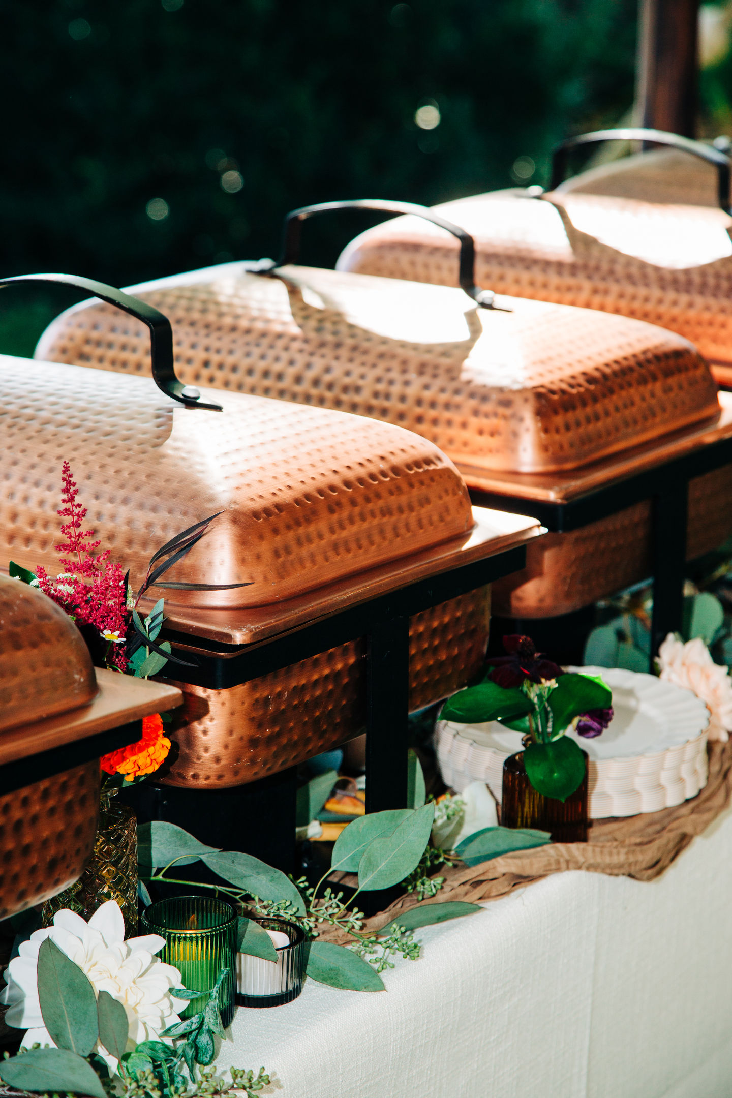 Wedding buffet table with copper serving trays and floral decorations designed by Tia’s Food of Love.