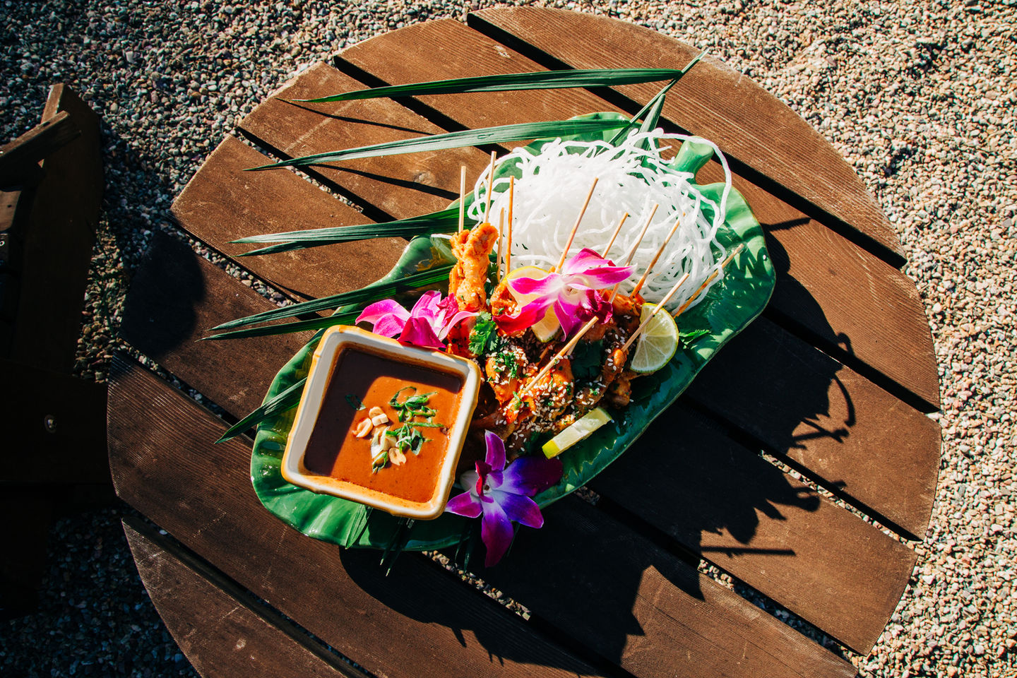 Tropical-themed wedding appetizer platter with flowers and dipping sauce by Tia’s Food of Love.