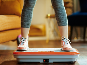 Closeup on young woman in fitness clothes in the modern house training using vibration power plate