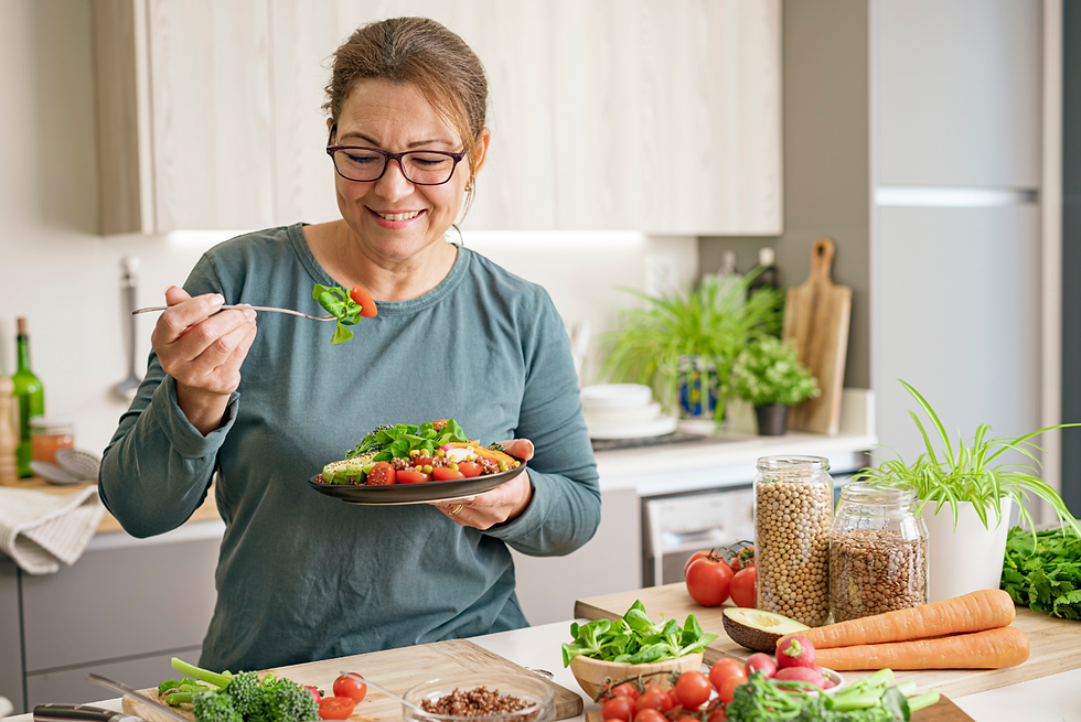 A mature woman eating a healthy vegan salad plate in the kitchen