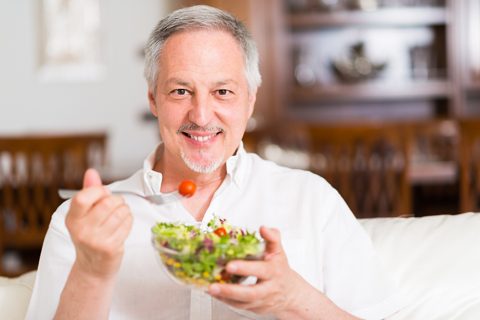 Portrait of a mature man eating a bowl of salad in his home