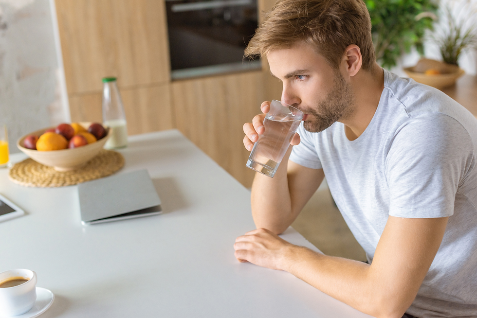 Young man drinking water at the kitchen table