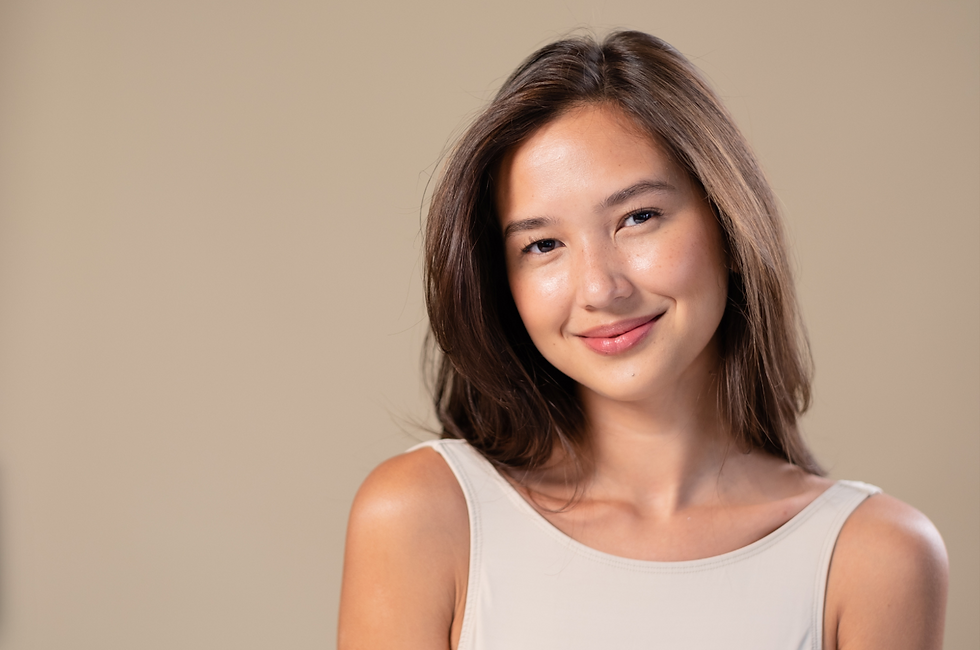Smiling woman wearing a white tank top on a beige background