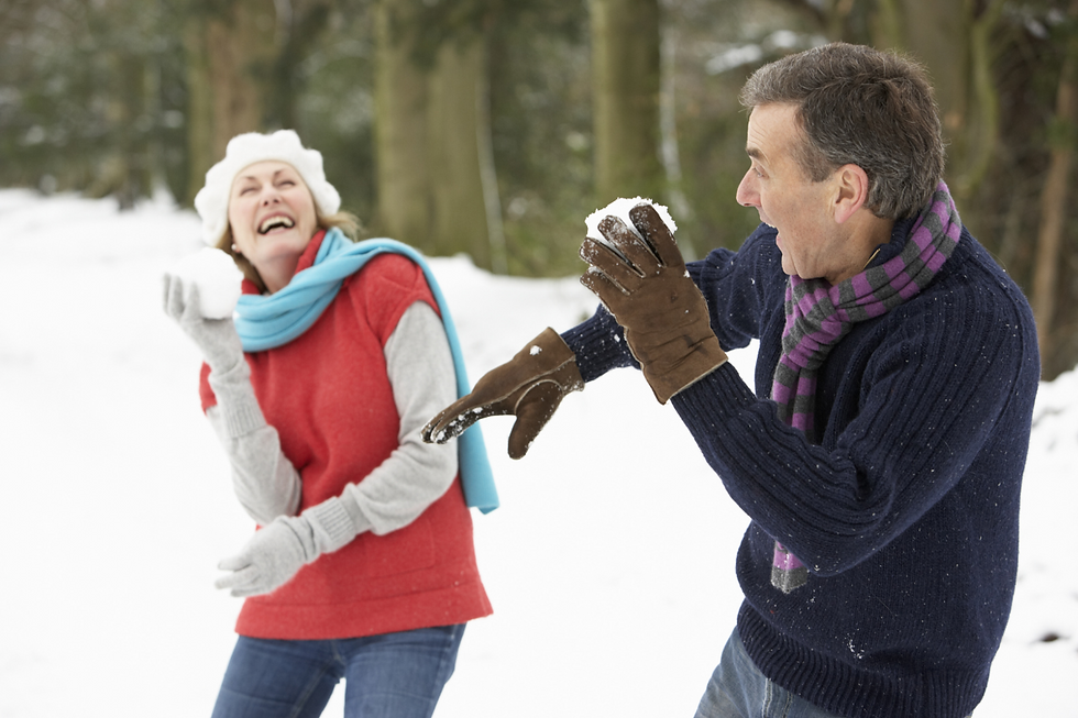 Senior couple laughing while having a snowball fight