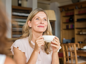 Mature woman holding a coffee cup at a cafeteria and looking away