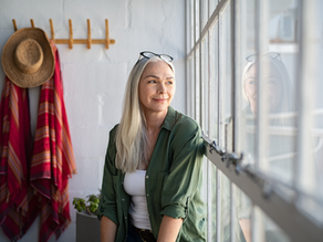 Smiling mature woman looking outside the window
