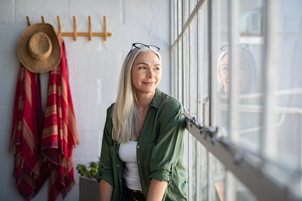 Smiling mature woman looking outside the window
