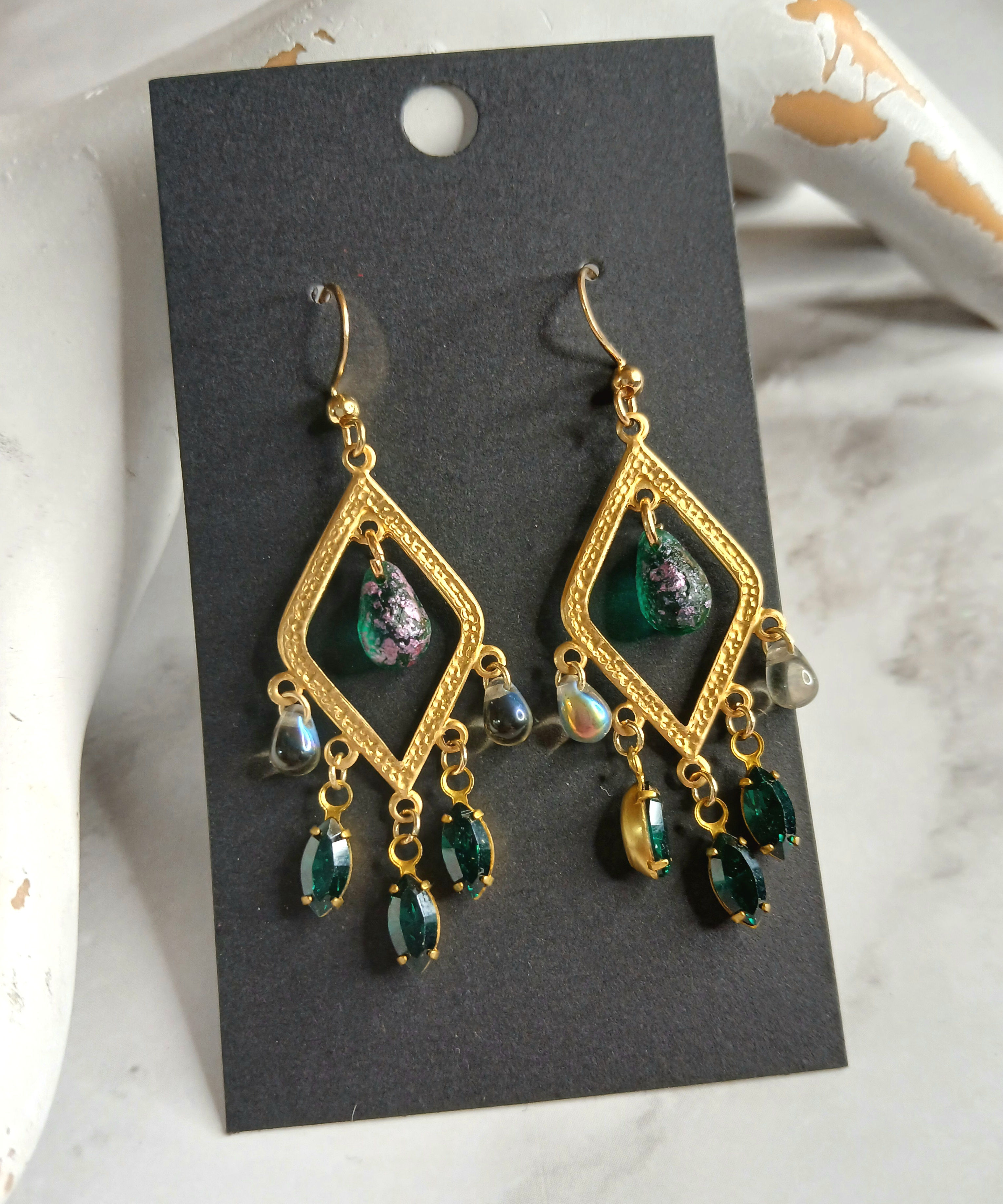 Golden diamond-shaped earrings strung with small green glass dangles