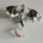 Brooch with a dragon showing red, white, and black wings.