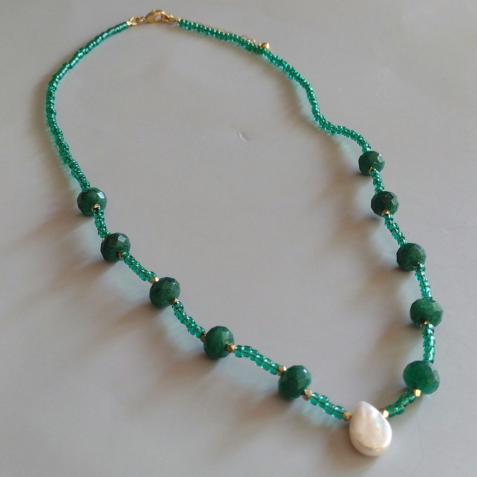 A green beaded necklace with a teardrop pearl and gold clasp and chain.
