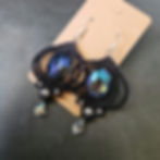 A pair of intricate black macrame earrings with large acrylic gems