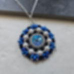 Circular beandwoven pendant in blue, black, and white.