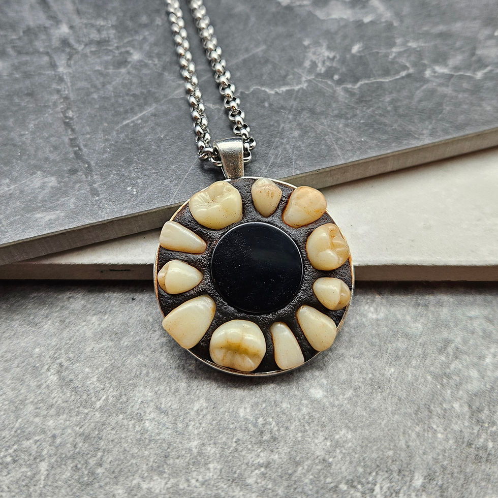 A silver pendant with a ring of teeth surrounding a small reflective surface.