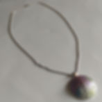 A large round dragon skin texture pendant in green, red, and blue, on a silver chain.