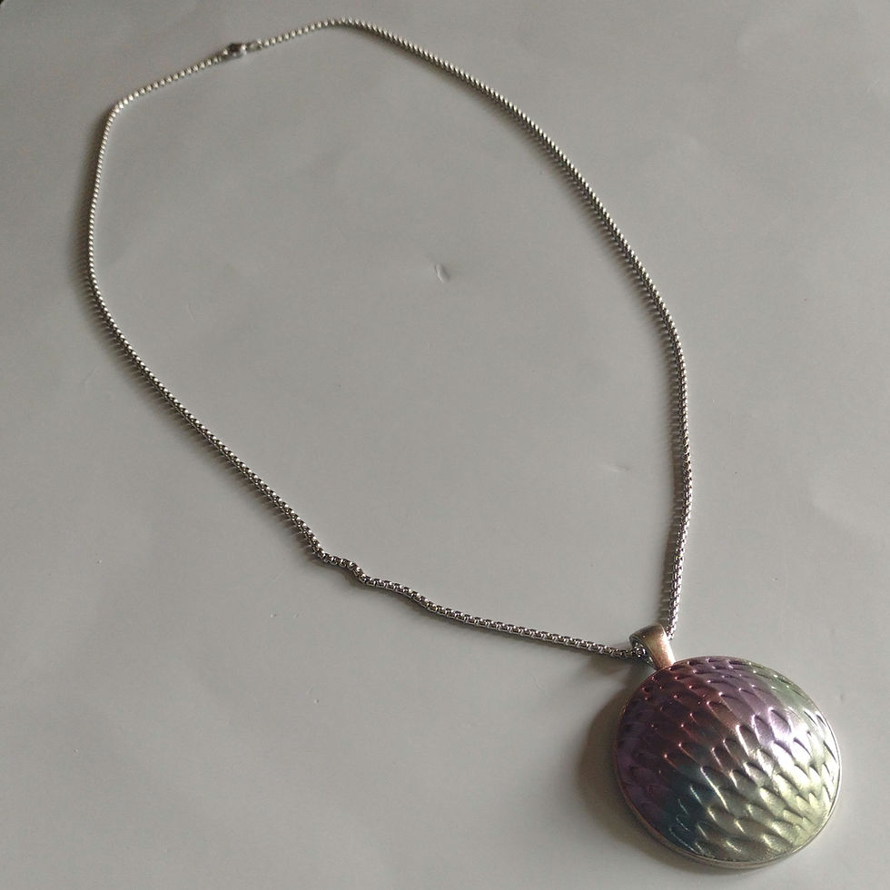 A large round dragon skin texture pendant in green, red, and blue, on a silver chain.