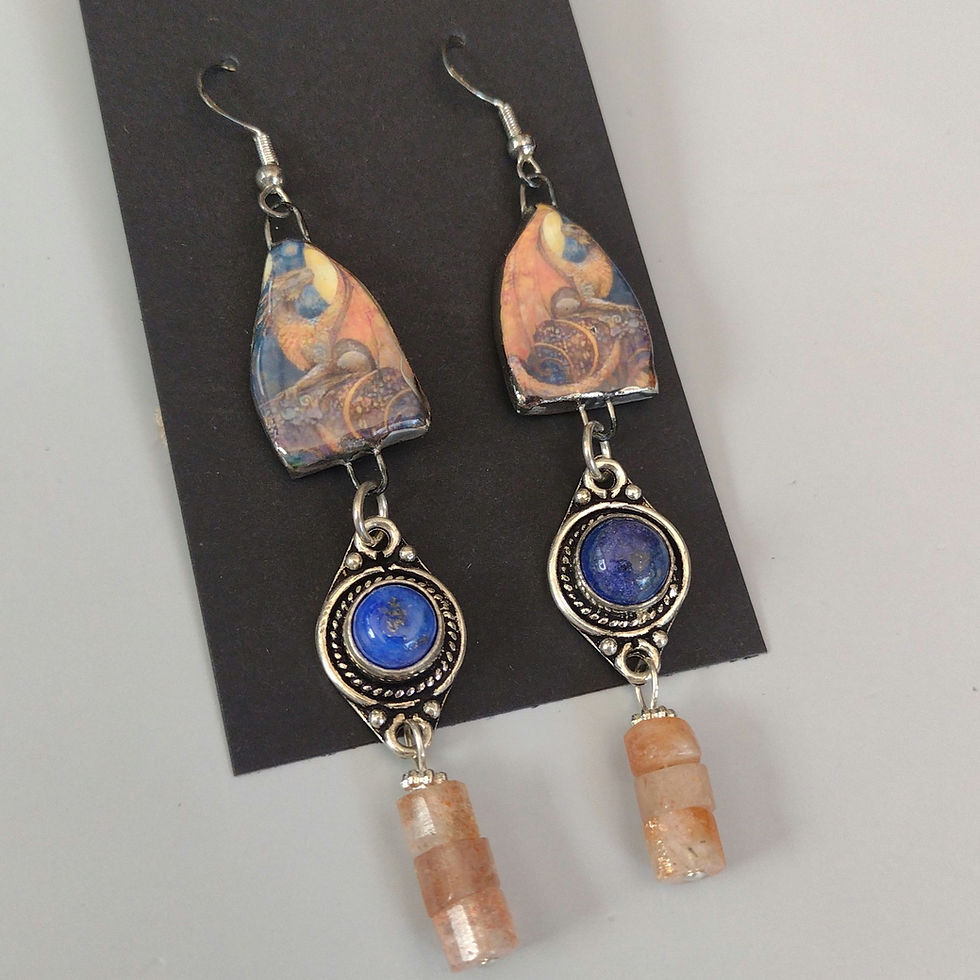 Earrings with orangey dragon against blue background, with bezeled lapis charm and sunstone tubes