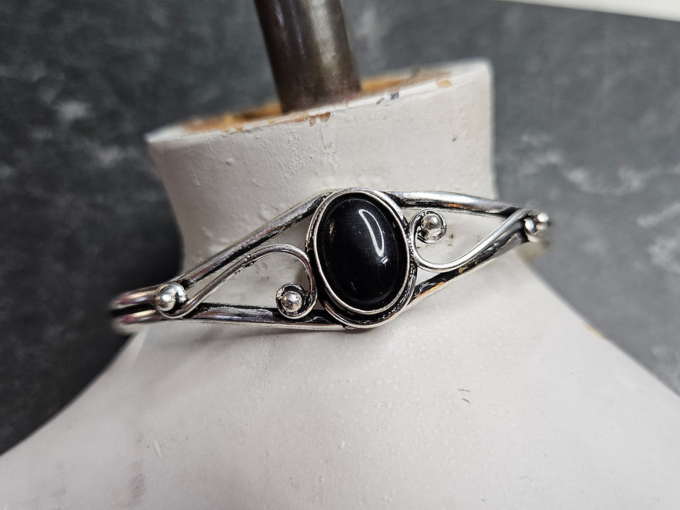 Bracelet cuff with onyx cabochon and silver swirled setting.