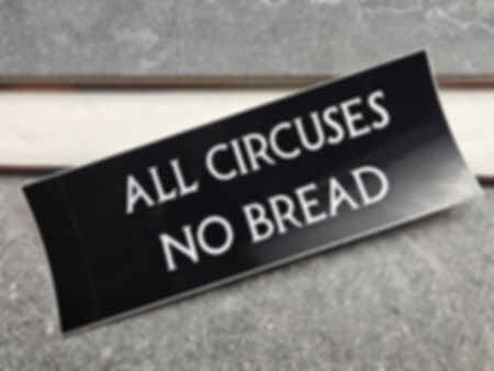 Rectagular black sticker with "All circuses No bread" in white text