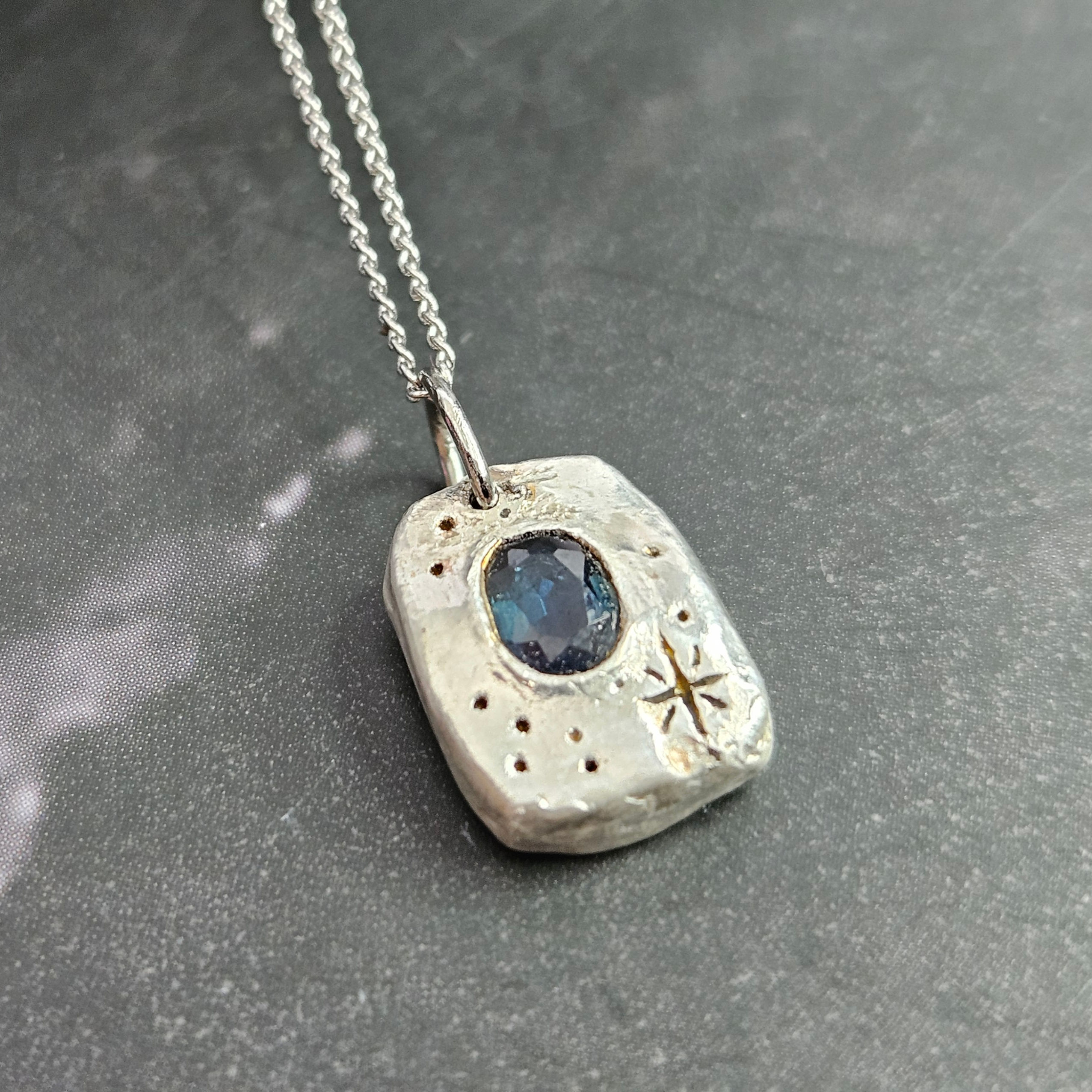 A sapphire and silver pendant necklace.