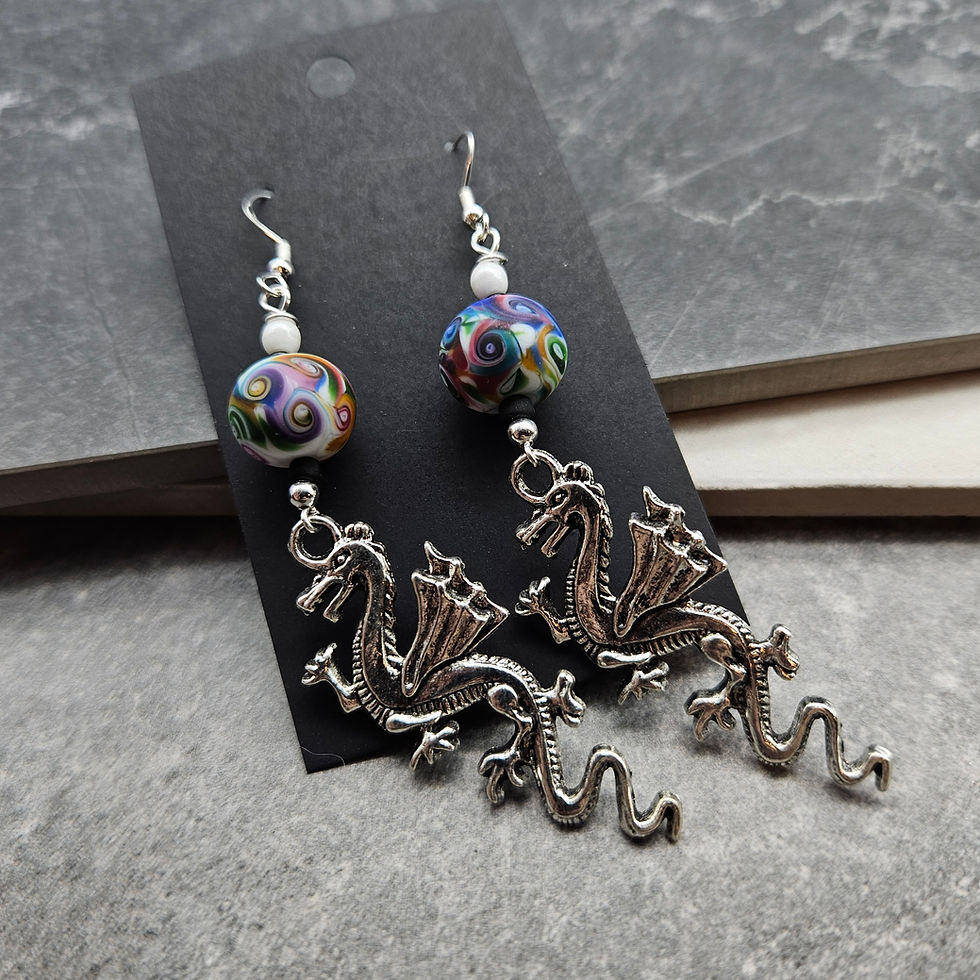 Earrings with large serpent dragon charms, white glass rounds, and matte rainbow swirl lampwork rondelles