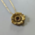 Gold flower polymer clay molded pendant with dark garnets in the center and a gold toned nickel free jump ring.
