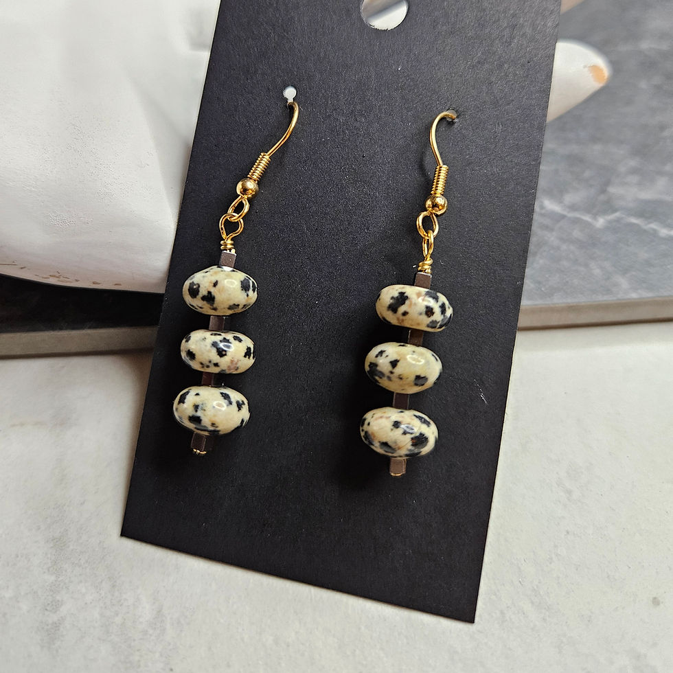 Dalmation quartz earrings with three quartz rounds separated by hematite cubes on gold tone ear hooks.