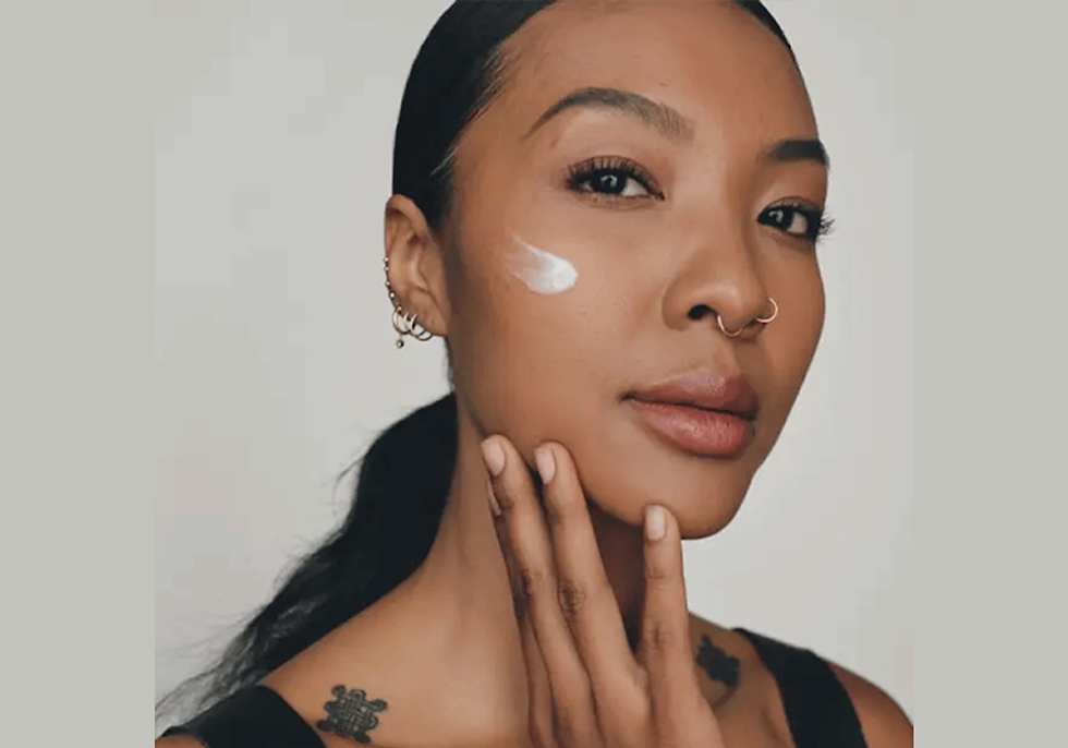 A woman applying cream to her skin