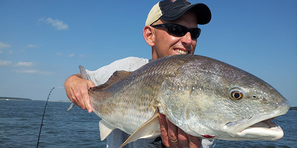 man holding a large fish out on the water