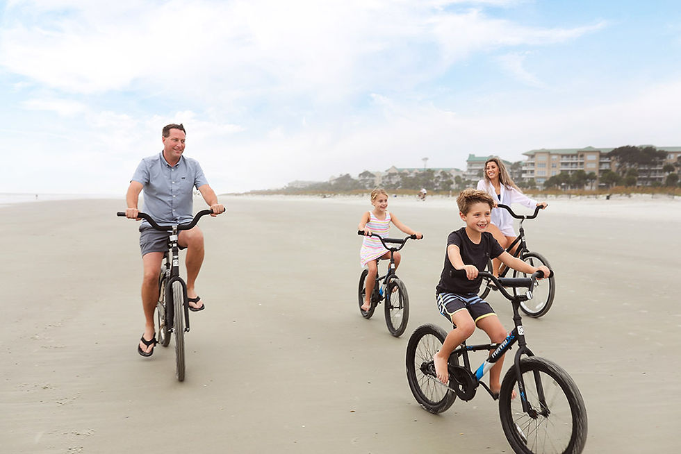 family riding bikes on beach