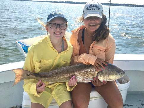 tow girls proudly hold a large fish on a boat