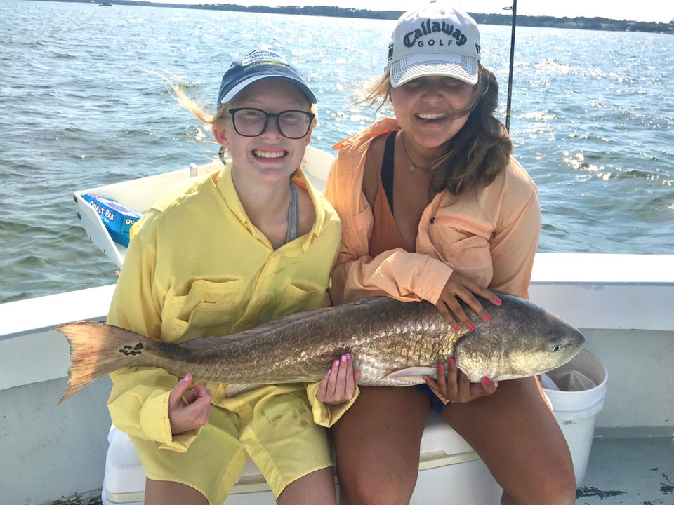 tow girls proudly hold a large fish on a boat