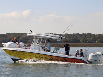 Boat in the water going fast with people on the bow