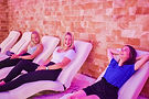 three young girls lounging on chairs inside of the pink salt room