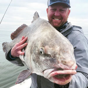 man holding a large fish with face towards the camera