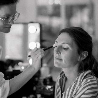 Black and white photo of a make up artist putting some eye shadow on the bride