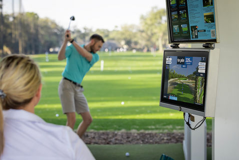 Girl watches man swing at Toptracer.