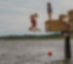 girl jumping from a dock into the water below