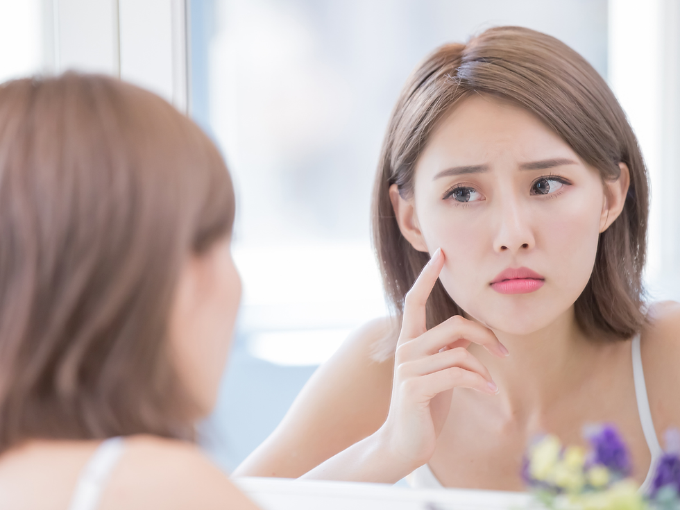 woman examining her skin in the mirror. Stop using toxic skincare