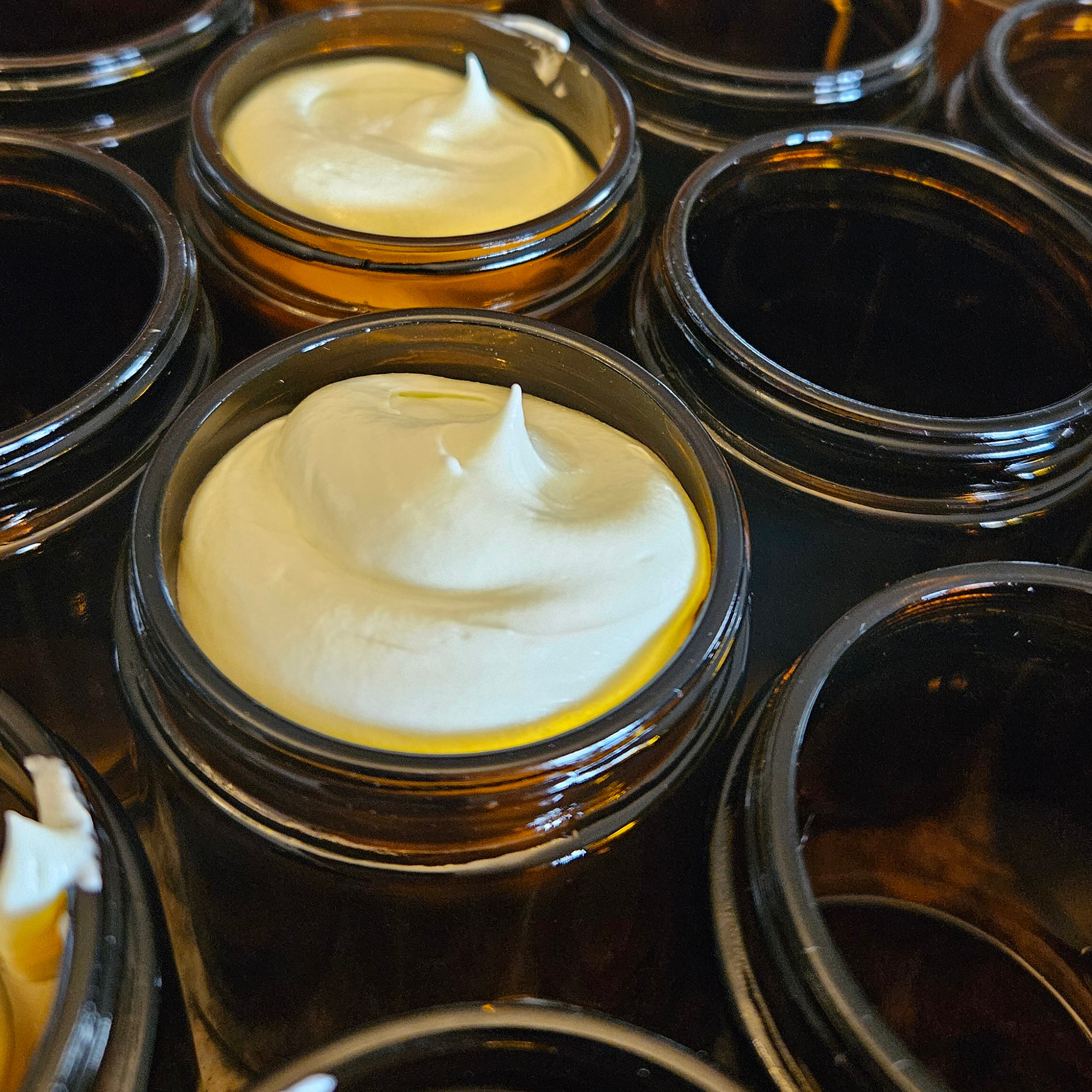 A row of amber glass jars with whipped tallow in them